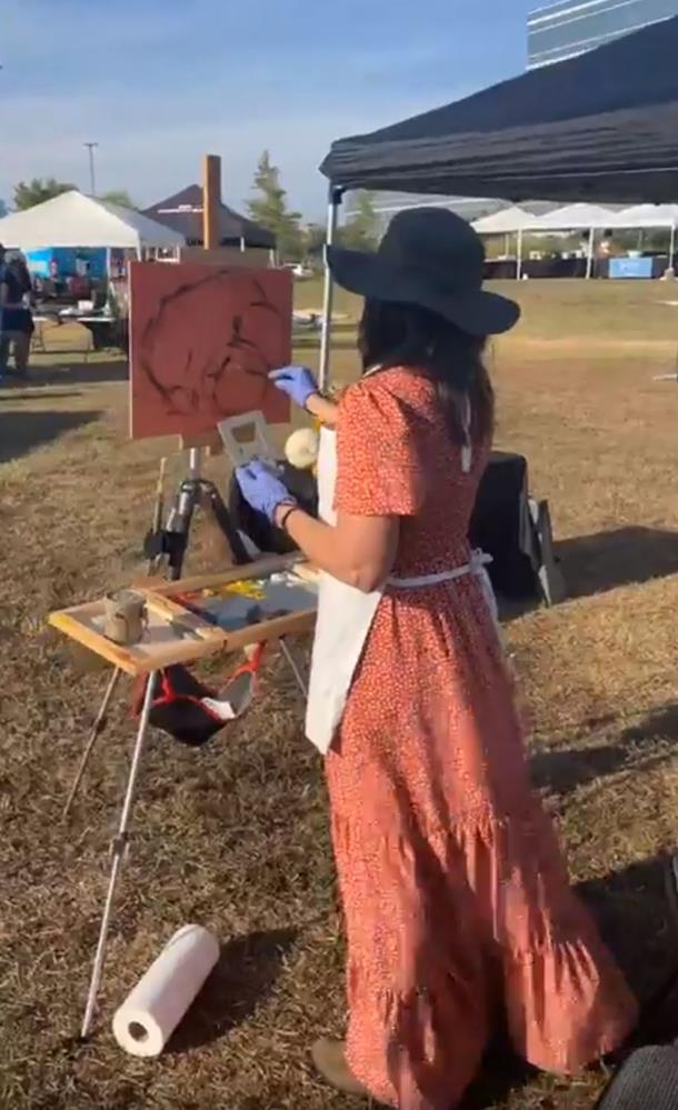 Lady in a dress plein air painting a still life